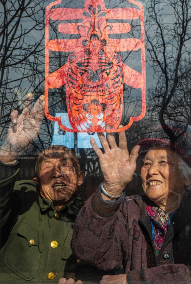 臘月里，霍州市師莊鄉(xiāng)馮南垣村村民師榮光(左)在災(zāi)后重建的新家里貼窗花。(霍州市委宣傳部供圖)