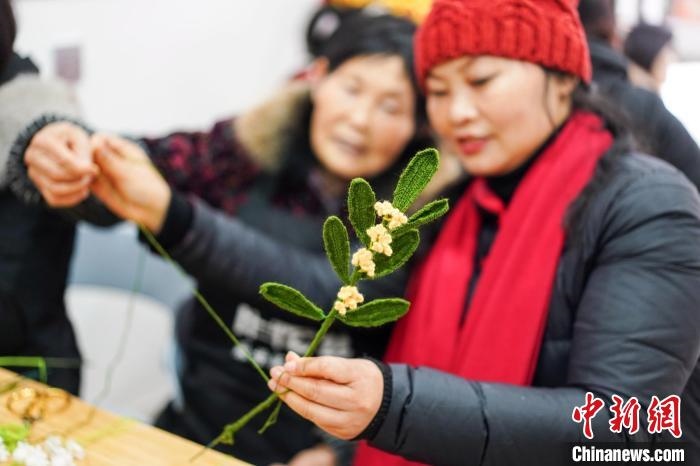 馮燕霞指導(dǎo)姐妹們鉤織月桂葉片。　古良駒 攝