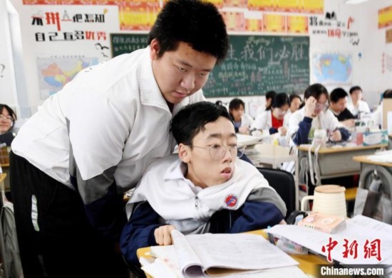 朱金祥(左)把鐘華強(qiáng)放到課堂座位上后，都要把他擺正好，確認(rèn)安全后才回到自己的座位上。 卓忠偉 攝