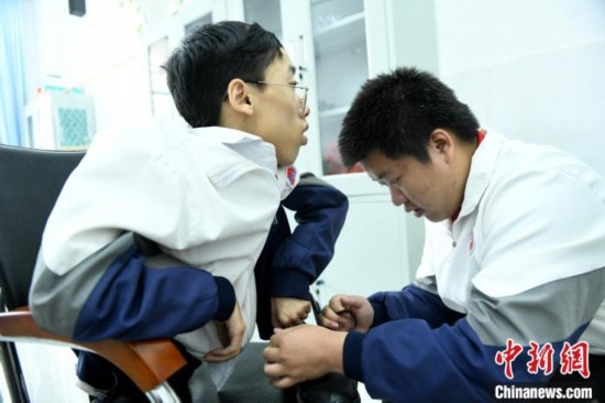 江西省南康中學(xué)北校區(qū)的高三學(xué)生朱金祥(右)正在給鐘華強(qiáng)(左)系好鞋帶。 卓忠偉 攝