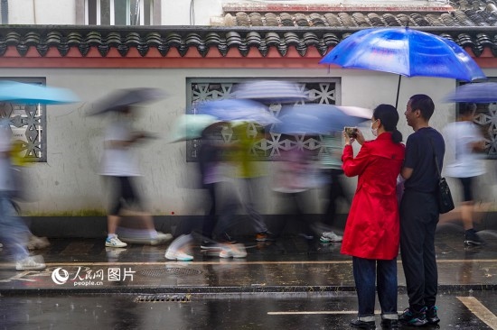 6月7日，在浙江省2023年普通高校招生考試鎮(zhèn)海中學考點，家長冒雨目送子女進入考場。人民網(wǎng) 章勇濤攝