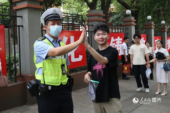 6月7日8時許，武漢中學考點門口，交警在維護秩序，并?？忌鸢耦}名。人民網(wǎng)記者 肖璐欣攝