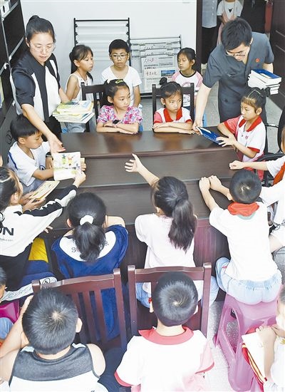  圖④：法院干警為留守兒童發(fā)放暑假讀物。