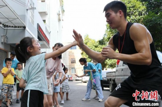 圖為大學(xué)生志愿者在組織孩子們參加體育健身活動。廖光福 攝