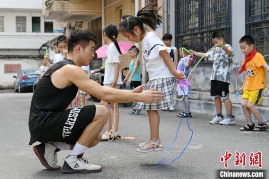 圖為大學(xué)生志愿者在教孩子們學(xué)跳繩。廖光福 攝
