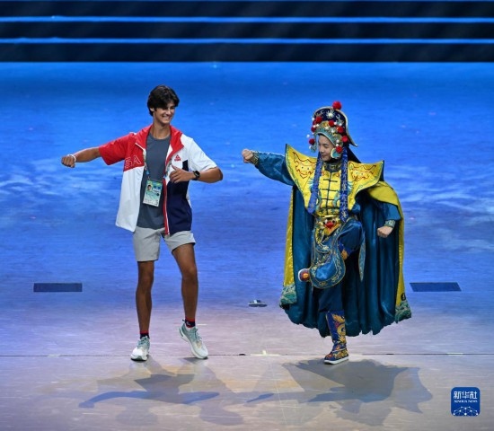 7月29日，美國運動員杜恩（左）在聯(lián)歡會現(xiàn)場與川劇演員互動。新華社記者 蔡湘鑫 攝