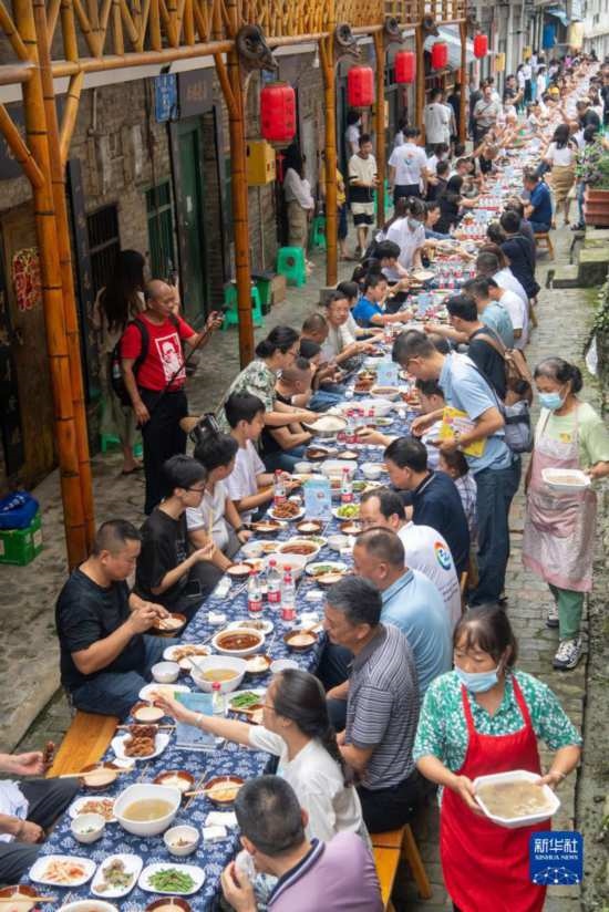 7月29日，在重慶市綦江區(qū)安穩(wěn)鎮(zhèn)，人們?cè)凇懊缂曳蚬?jié)”上吃長桌宴。新華社記者 唐奕 攝