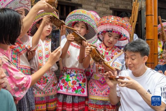 7月29日，在重慶市綦江區(qū)安穩(wěn)鎮(zhèn)，當(dāng)?shù)鼐用裨凇懊缂曳蚬?jié)”上用傳統(tǒng)習(xí)俗向游客表達(dá)祝福。新華社記者 唐奕 攝