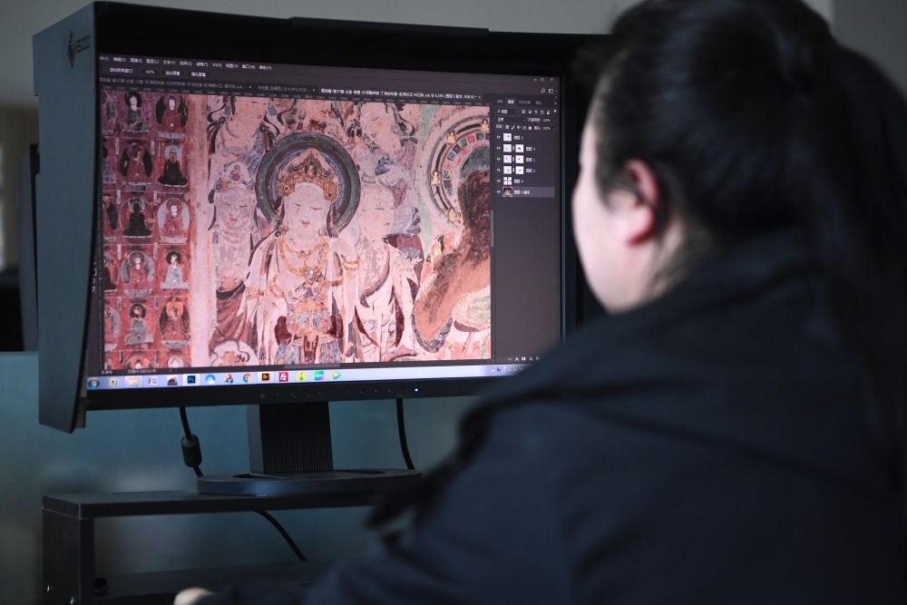 敦煌研究院文物數(shù)字化保護(hù)團(tuán)隊(duì)圖像處理人員年海麗在拼接壁畫(huà)圖像（2023年4月25日攝）。數(shù)字化探索為莫高窟的保護(hù)與傳承開(kāi)辟了全新路徑，數(shù)字技術(shù)讓敦煌文物走出洞窟，跨出國(guó)門(mén)，走向“永久保存、永續(xù)利用”。新華社記者 陳斌 攝