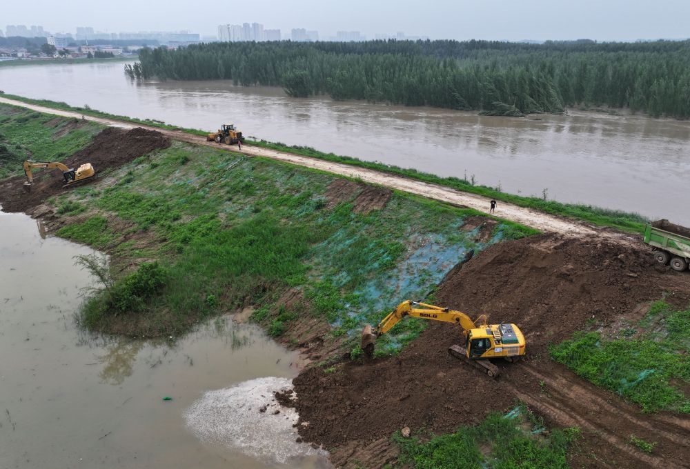 工人操作機(jī)械在白溝河左堤白溝新城高橋村段進(jìn)行除險(xiǎn)加固作業(yè)（8月4日攝，無(wú)人機(jī)照片）。新華社記者 朱旭東 攝