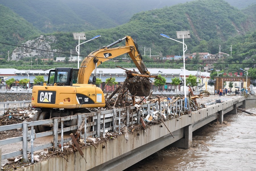 8月1日，在北京市門頭溝區(qū)水峪嘴村村口，一臺(tái)挖掘機(jī)在清理阻斷橋梁交通的雜物。目前該條道路已經(jīng)疏通完成。新華社記者 鞠煥宗 攝
