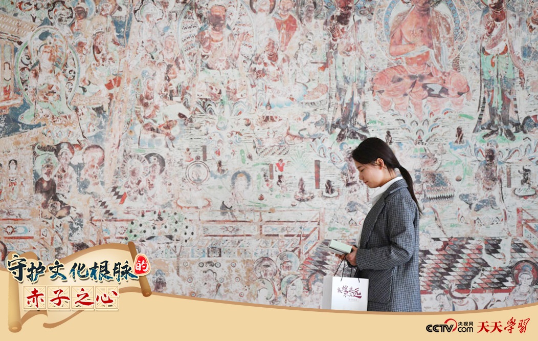 2023年4月25日，敦煌研究院文物數(shù)字化保護(hù)團(tuán)隊(duì)創(chuàng)意營銷人員廖雪婷從一幅高保真復(fù)制壁畫前走過。