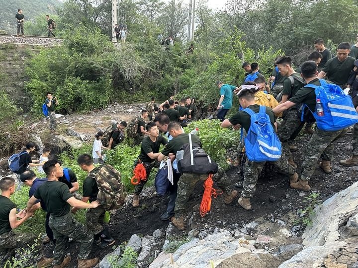 8月2日，Z180次受困列車(chē)的旅客在武警北京總隊(duì)機(jī)動(dòng)第三支隊(duì)官兵的幫助下徒步前往轉(zhuǎn)運(yùn)客車(chē)（手機(jī)照片）。新華社記者 王艷剛 攝