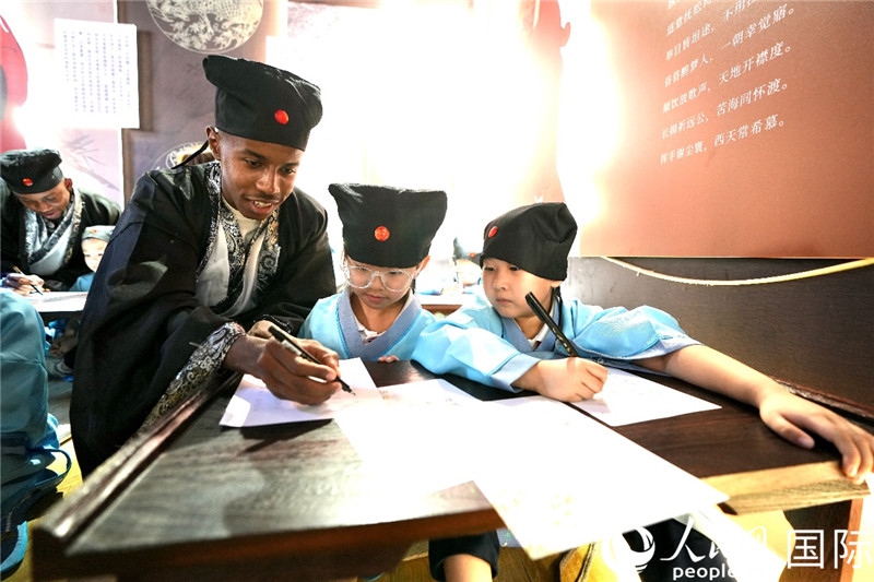 圖為選手與同學們一起寫書法。人民網(wǎng) 盧鵬宇攝
