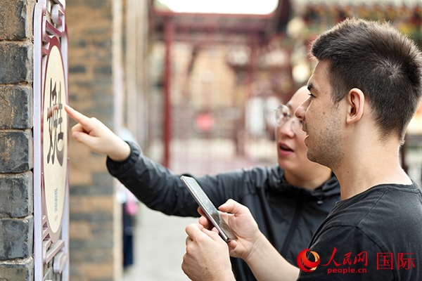 選手安德烈（俄羅斯）在老師指導(dǎo)下學(xué)習(xí)墻壁上張貼的生僻字。人民網(wǎng) 盧鵬宇攝
