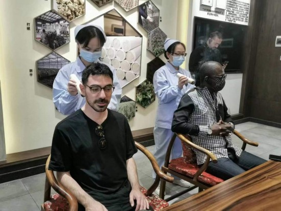 2023“一帶一路”媒體合作論壇聯(lián)合采訪團團員在九牛草展示館體驗艾灸。（本報記者 黃超攝）