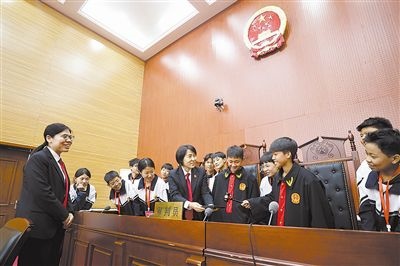 圖③：同學(xué)們穿法袍、敲法槌，爭做“小法官”。