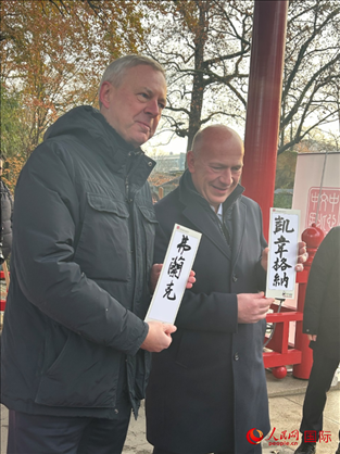 柏林市長韋格納（右）、動物園監(jiān)事會主席布魯克曼（左）手持中國文化中心工作人員現(xiàn)場手書的中文名字。人民網記者 徐馨攝