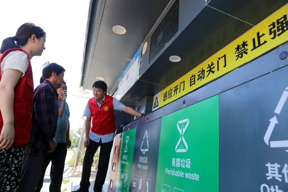 在安徽省合肥市長豐縣莊墓鎮(zhèn)棗林社區(qū)，志愿者指導(dǎo)居民使用智能垃圾分類回收設(shè)備（2023年9月1日攝）。新華社記者 曹力 攝