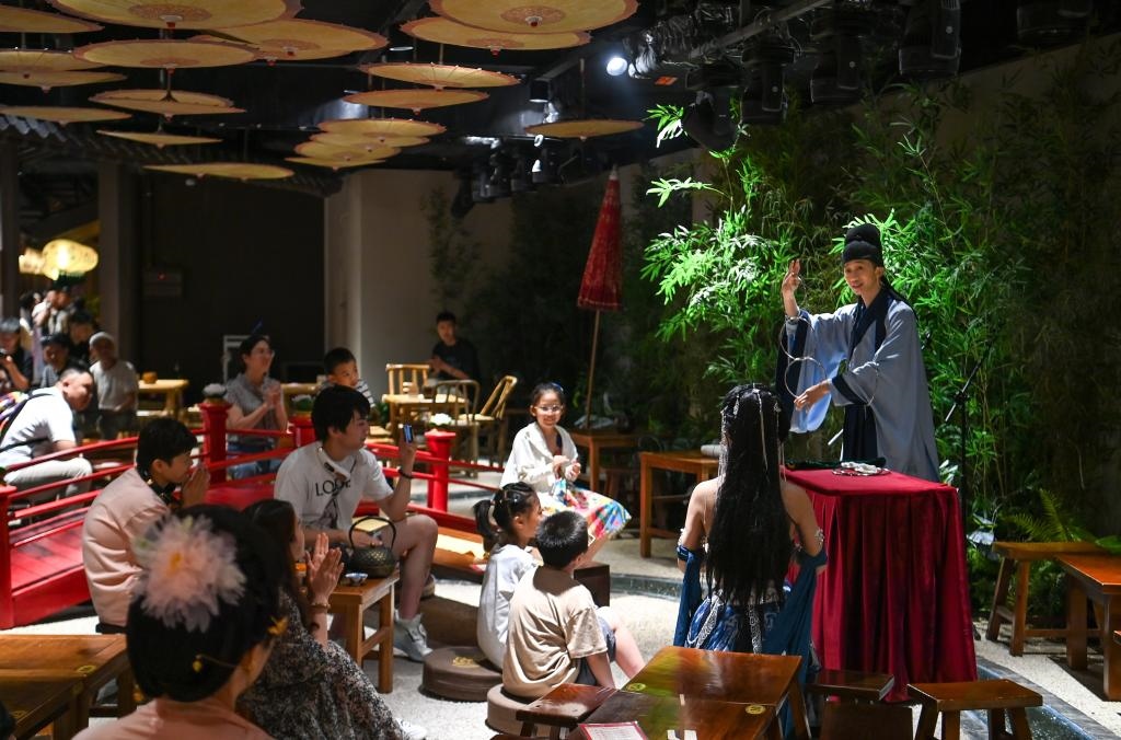 游客在長(zhǎng)安十二時(shí)辰主題街區(qū)觀看唐風(fēng)演藝《大唐曲藝》。新華社記者鄒競(jìng)一 攝