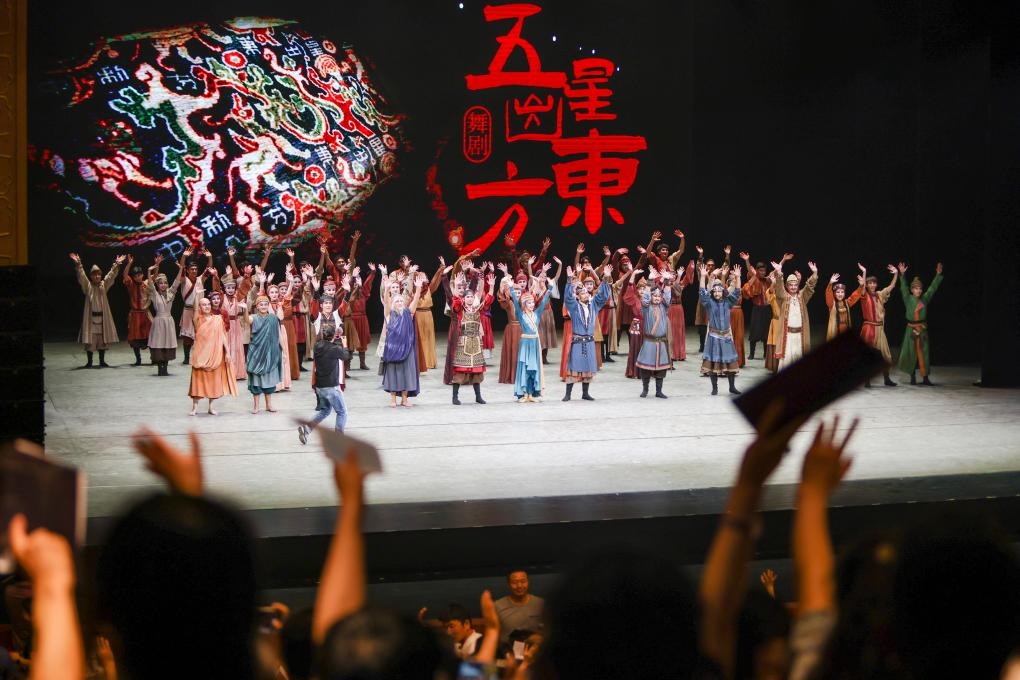 2023年7月31日，新疆和田地區(qū)新玉歌舞團(tuán)在烏魯木齊京劇院演出舞劇《五星出東方》后和觀眾互相揮手致意。這場演出是第六屆中國新疆國際民族舞蹈節(jié)的參演劇目之一，曾榮獲國家“文華獎(jiǎng)”等。新華社記者 郝昭 攝