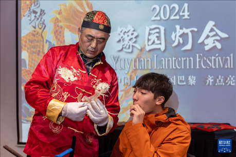 1月28日，在上海豫園舉行的民俗活動(dòng)上，美國(guó)馬斯卡廷中學(xué)學(xué)生在非遺傳承人的指導(dǎo)下吹糖偶。 新華社記者 王翔 攝