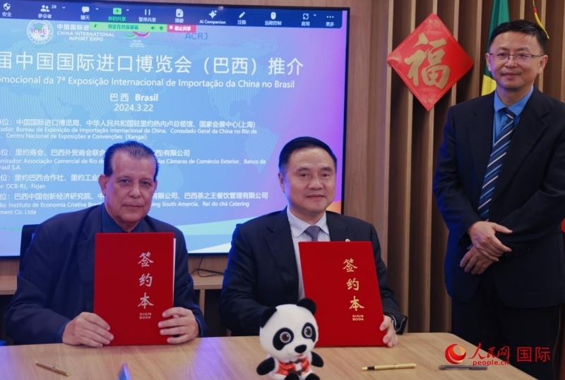 巴西外貿(mào)商會聯(lián)合會會長阿代爾·羅伯托（左）與中國國際進(jìn)口博覽局副局長吳政平（中）現(xiàn)場簽訂協(xié)議。人民網(wǎng)記者 宋亦然攝