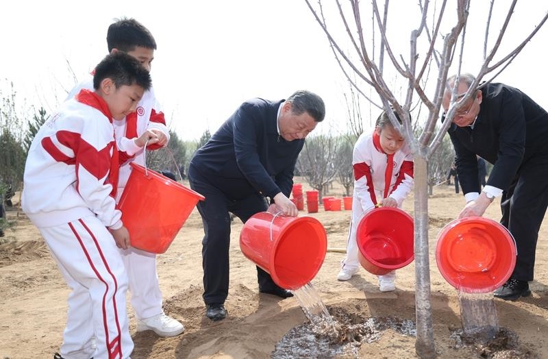 2024年4月3日，習(xí)近平總書記同少先隊(duì)員一起給剛栽下的樹苗澆水。