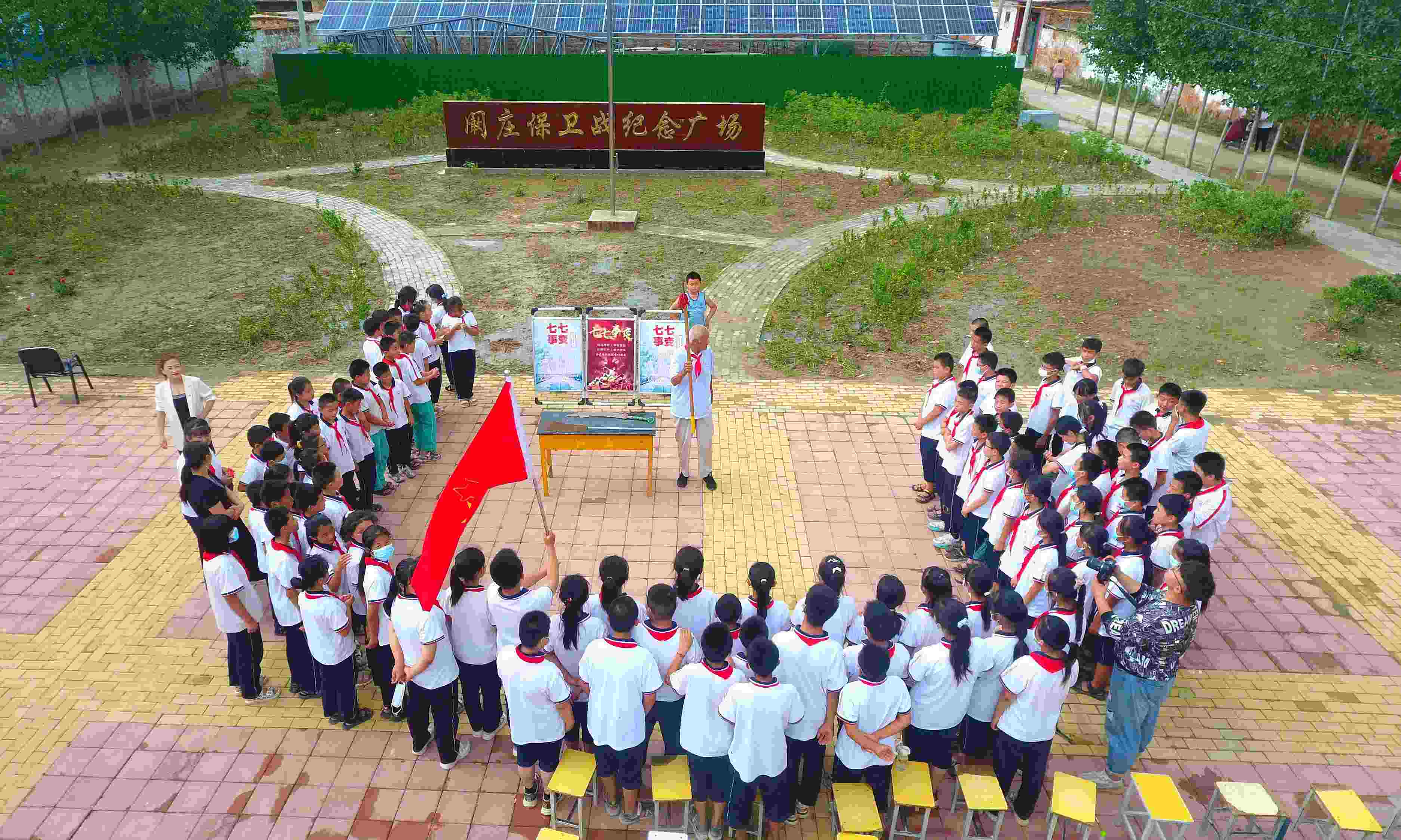 2022年7月6日，山東省聊城市，在茌平區(qū)菜屯鎮(zhèn)闞莊村的闞莊保衛(wèi)戰(zhàn)紀念廣場，闞莊保衛(wèi)戰(zhàn)親歷者王光木老人為小學生們講述抗戰(zhàn)故事，展示大刀、長矛。