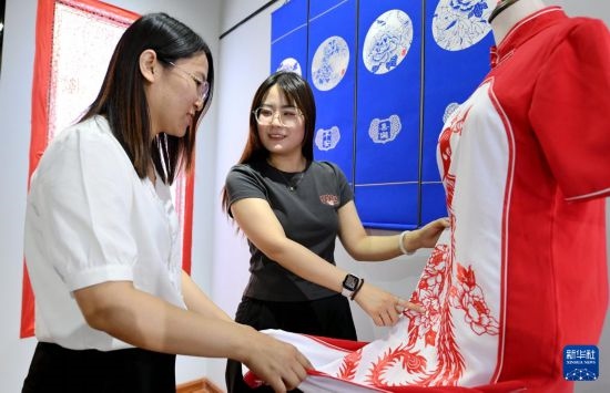 5月31日，在衡水市阜城縣一家剪紙工作室，游客在觀賞帶有剪紙?jiān)氐钠炫邸? width=