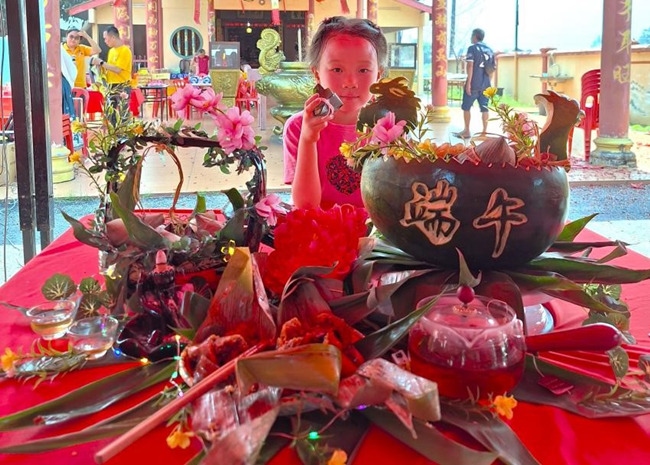 小朋友展示學(xué)裹粽子的成品照。組委會供圖