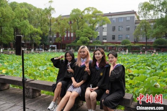 6月19日，時值一年畢業(yè)季，四川大學望江校區(qū)荷花池里的荷花盛開，成為了畢業(yè)生們的打卡圣地，吸引了眾多畢業(yè)生拍照留念。圖為畢業(yè)生在荷花池邊拍照留念。中新社記者 安源 攝