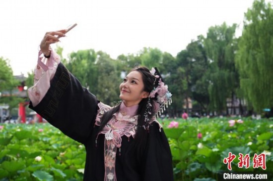 6月19日，時值一年畢業(yè)季，四川大學望江校區(qū)荷花池里的荷花盛開，成為了畢業(yè)生們的打卡圣地，吸引了眾多畢業(yè)生拍照留念。圖為畢業(yè)生在荷花池邊拍照留念。中新社記者 安源 攝