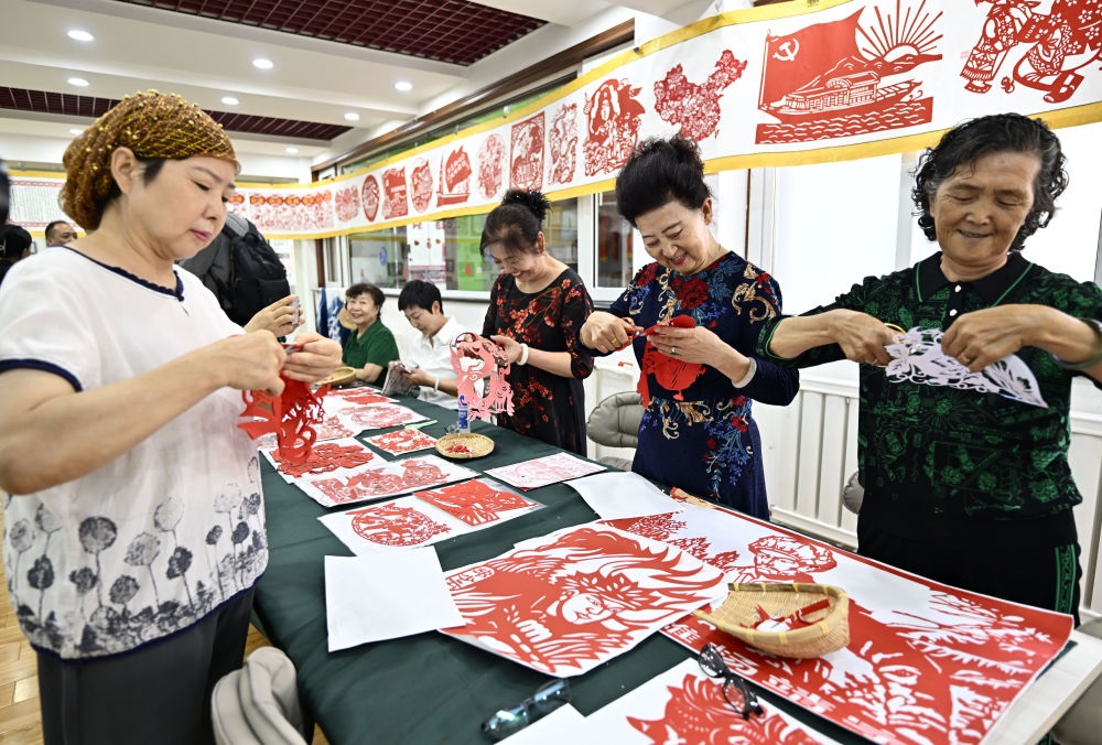 6月19日，長城花園社區(qū)居民在社區(qū)“才藝堂”制作剪紙。