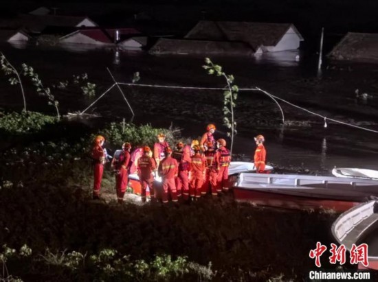  7月6日凌晨3時(shí)，在湖南岳陽華容縣團(tuán)洲垸洞庭湖一線堤防，救援人員剛剛完成一次救援任務(wù)，遠(yuǎn)處是被淹的民房。中新社記者 白祖偕 攝