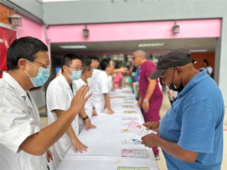 援圭醫(yī)療隊隊員們在啟動儀式上為當?shù)孛癖姺职l(fā)宣傳手冊。中國援助圭亞那醫(yī)療隊供圖