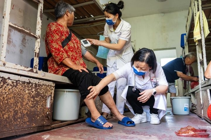 2024年7月30日，在湖南省湘潭縣河口中學(xué)安置點(diǎn)，醫(yī)務(wù)人員為受洪水影響而轉(zhuǎn)移安置的群眾檢查身體。 新華社記者 陳思汗 攝