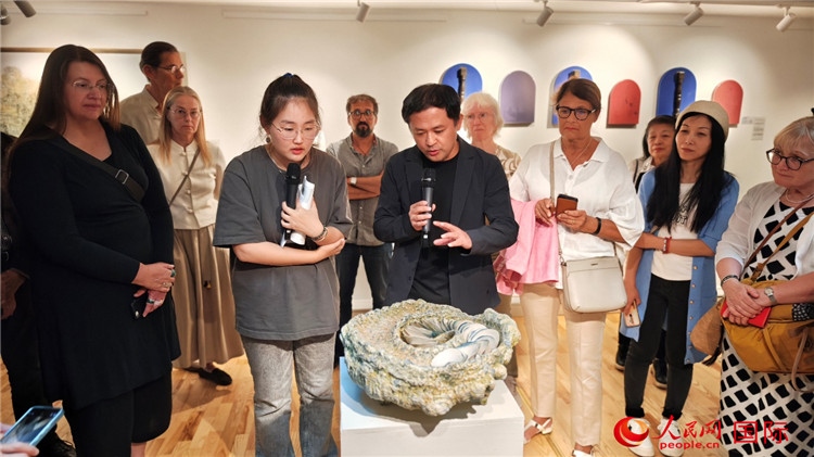 參展人、景德鎮(zhèn)陶瓷大學(xué)設(shè)計(jì)藝術(shù)學(xué)院副院長(zhǎng)余劍峰（中）向來(lái)賓介紹參展作品。人民網(wǎng)記者 殷淼攝