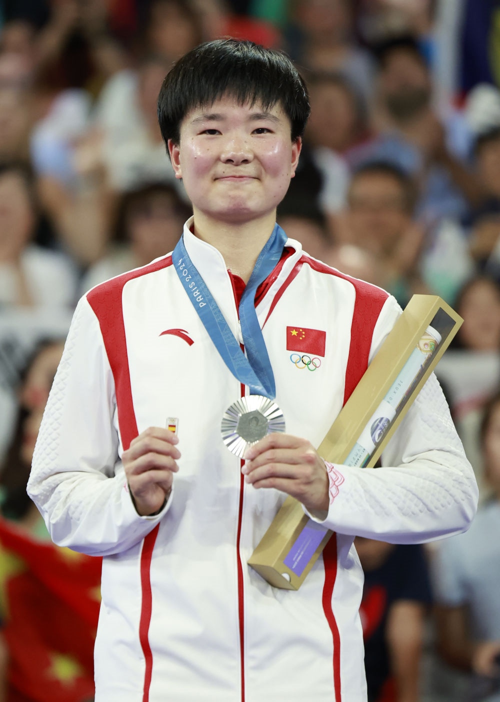 巴黎奧運會羽毛球女子單打亞軍、中國選手何冰嬌在頒獎儀式上一手握著銀牌，一手握著西班牙奧委會徽章（2024年8月5日攝）。新華社記者 任正來 攝