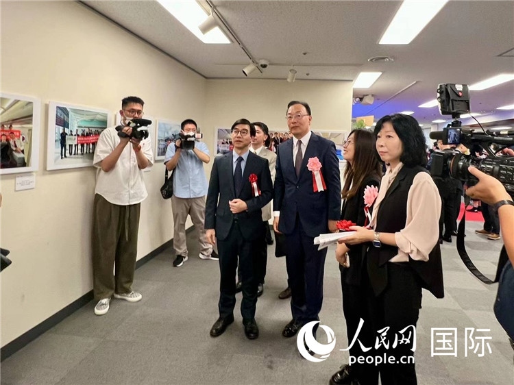 中國國際航空日韓地區(qū)支社支社長馮力為中國駐日本大使館臨時代辦施泳等嘉賓介紹展出圖片。人民網(wǎng) 許可攝
