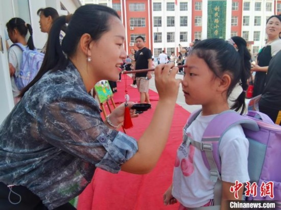 圖為衡水市利民路小學(xué)，老師為學(xué)生點(diǎn)朱砂痣，寓意開啟智慧。張松 攝