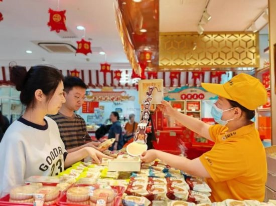 北京稻香村一家門店內(nèi)，售貨員向顧客展示新上市的月餅禮盒。（受訪者供圖）