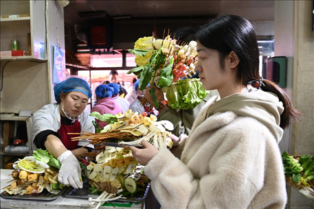 游客挑選好麻辣燙菜品后排隊(duì)等待加工。新華社記者 范培珅 攝