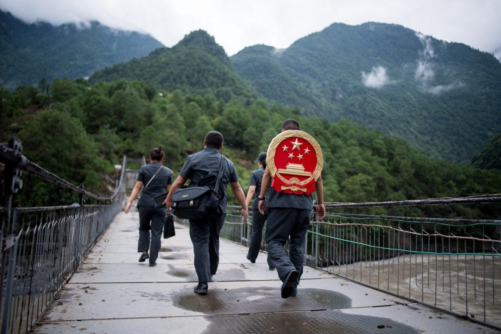 云南省怒江傈僳族自治州貢山縣人民法院法官鄧興背著國徽與同事們跨過怒江（2019年8月30日攝）。怒江高山峽谷眾多，交通不便，為方便群眾、更好地開展法律服務(wù)，背著國徽攀高山、過索橋、躲落石、鉆老林……成為鄧興法官的工作常態(tài)。新華社記者 江文耀 攝