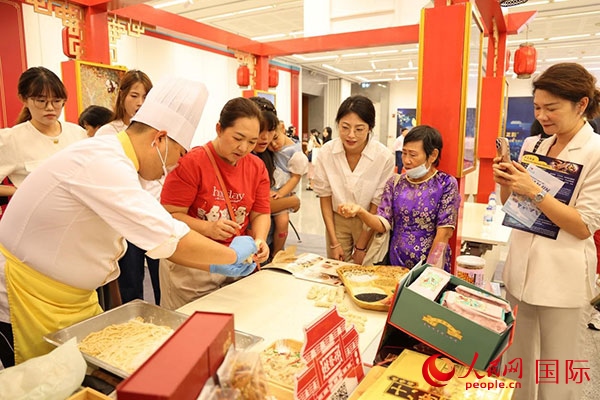 演出前，在天津桂發(fā)祥十八街麻花制作技藝非遺體驗(yàn)展臺前，泰國民眾體驗(yàn)天津麻花制作。人民網(wǎng)記者 楊一攝