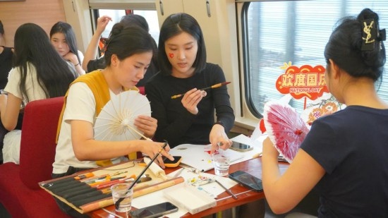 10月1日，旅客們在G1634次列車上給油紙傘作畫。新華社記者周義 攝