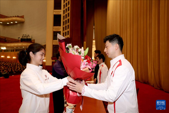 11月15日，一名學(xué)生代表在報(bào)告會(huì)上向乒乓球運(yùn)動(dòng)員馬龍（右）獻(xiàn)花。新華社記者 李明 攝
