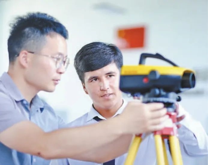 在塔吉克斯坦首都杜尚別的魯班工坊，來自天津城市建設管理職業(yè)技術(shù)學院的老師（左）為當?shù)貙W生提供指導。新華社記者 鄭開君 攝