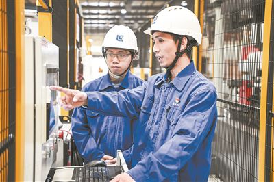 在廣西柳工機械股份有限公司生產(chǎn)車間內(nèi)，一名高級技師（右）給徒弟講解數(shù)控設(shè)備操作細節(jié)。新華社記者 曹祎銘攝