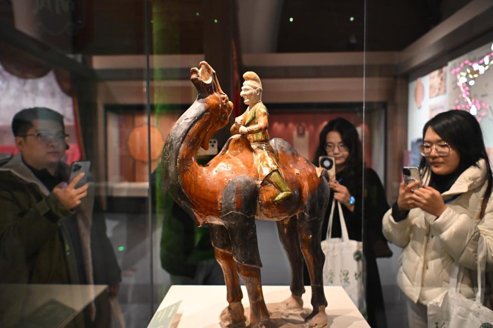 1月15日，觀(guān)眾在拍攝“長(zhǎng)安三萬(wàn)里——陜西唐代文物精華展”展出的三彩胡人騎駝俑。（新華社記者 孫凡越 攝）